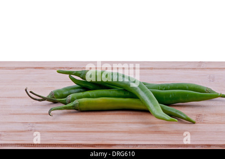 Pila di peperoncini verdi su invecchiato boarrd chopping e sfondo bianco. orizzontale Foto Stock