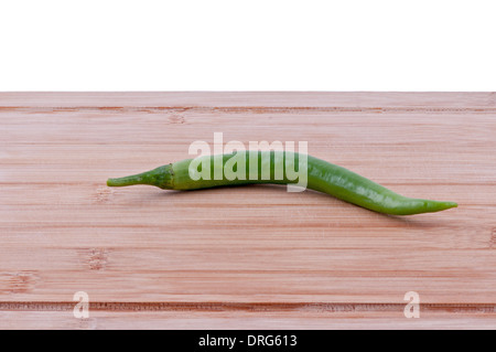Peperoncini verdi su invecchiato boarrd trinciatura su sfondo bianco orizzontale. Foto Stock
