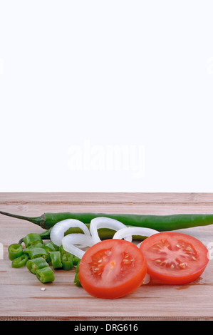 Un trito di peperoncini verdi, pomodori a fettine e le cipolle tagliate a fette in età boarrd chopping e sfondo bianco verticale. Foto Stock