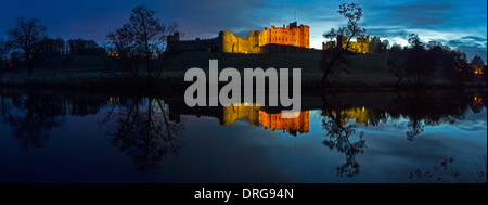 Una vista del tramonto di Alnwick Castle in Northumberland in inverno si riflette nel fiume Aln Foto Stock