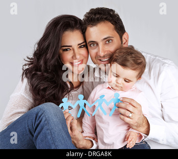 Ritratto di carino famiglia araba seduta in studio e tenendo in mano uomo blu a forma di carta di incollaggio, collegamento di persone Foto Stock