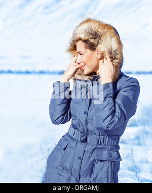 Ritratto di ragazza carina all'aperto in inverno, guardando dal lato, felice e uno stile di vita attivo, abiti alla moda per l'inverno Foto Stock