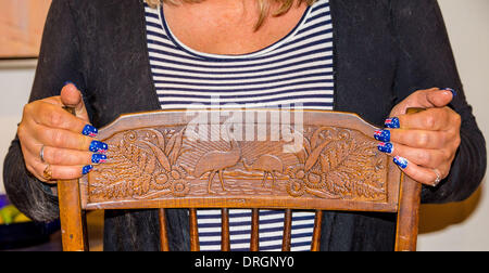 Le mani con le unghie verniciate con bandiere australiano poste su antichi intagliati Australiana sedia. Foto Stock