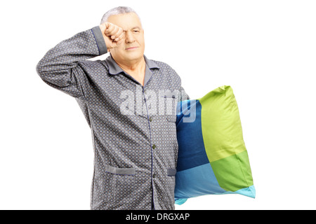 Assonnato uomo di mezza età in pigiama tenendo un cuscino Foto Stock
