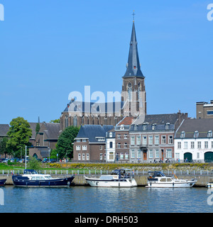 Il fiume Maastricht Mosa Maas ormeggiava motoscafi, chiesa simbolo della guglia e torre oltre in una soleggiata giornata estiva di cielo blu a Limburgh Paesi Bassi Europa e UE Foto Stock