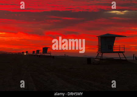 Bagnino torri presso Huntington Beach California stagliano contro un rosso infuocato cielo come il sorgere del sole su una nuova alba Foto Stock