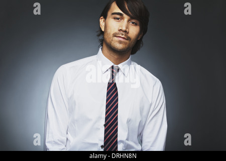 Ritratto di bel giovane maschio executive business fissando fotocamera contro uno sfondo grigio. Asian young business. Foto Stock