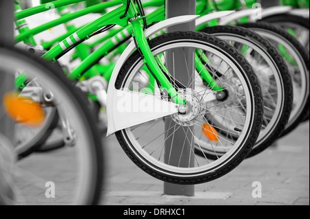 Scena urbana con verde biciclette a noleggio in una stazione di velo Foto Stock