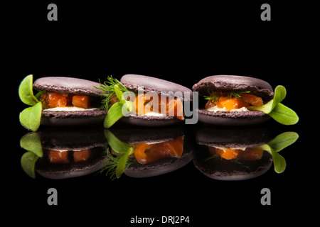 Amaretti riempito con salmone e verde su sfondo nero Foto Stock