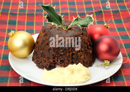 Tradizionale budino di Natale con un rametto di agrifoglio e brandy di burro - studio shot Foto Stock