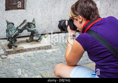 Un giovane turista prende le fotografie di Wroclaw il famoso Bronzo poco gnomi, nani o krasnale statuette. Foto Stock
