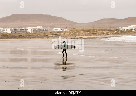 Surfer passeggiate fuori le onde del mare portando la sua tavola da surf surf boarding stanco surfers che trasportano le tavole da surf SURF BEACH Foto Stock