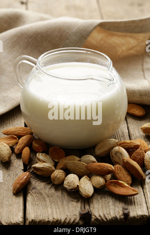 Latte di Mandorla in una caraffa di vetro con frutti a guscio interi Foto Stock