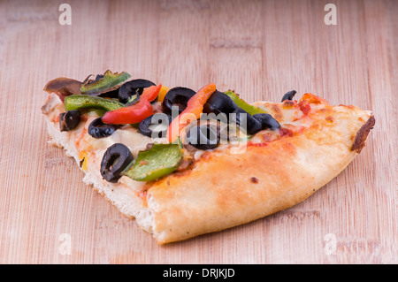 Pizza vegetariana pezzo su un tagliere, topping includono Olive Pomodori, pepe e formaggio Foto Stock