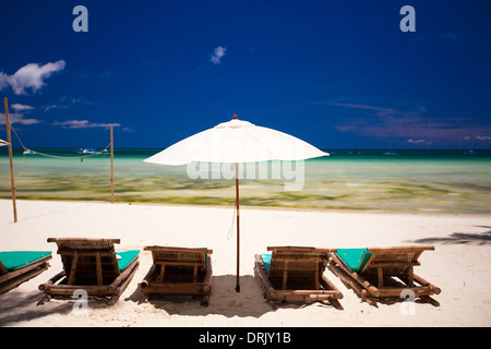 Sedie a sdraio e ombrelloni sulla spiaggia di sabbia bianca di fronte alla laguna Foto Stock