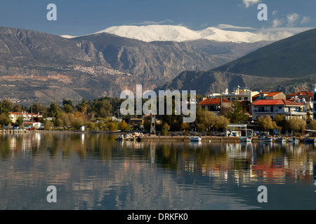 La città di Itea, Grecia, alle cime innevate del monte Parnasso in background e l'antico villaggio di Delphi sulle sue pendici Foto Stock