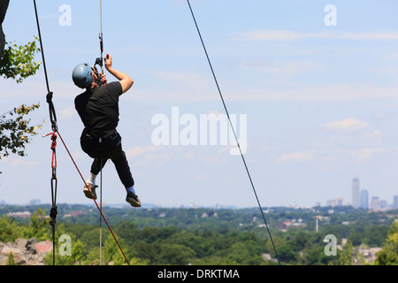 Uomo con lesioni del midollo spinale con adaptive arrampicata attrezzature per la palestra di roccia Foto Stock