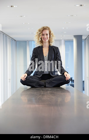 Germania, Neuss, Young business donna seduta con le gambe incrociate sul tavolo Foto Stock