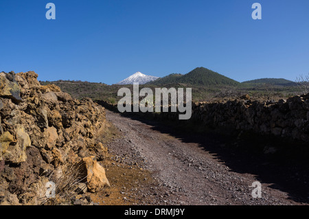 Pista sterrata in Santiago del Teide con le vette picco del Teide Nella distanza, Tenerife, Isole Canarie, Spagna. Foto Stock