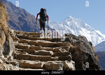 Un trekker passaggi di arrampicata sul campo base Everest trek, Nepal, con Everest oltre Foto Stock