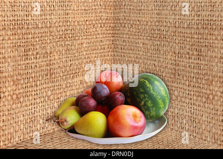 Piatto pieno di frutti diversi cocomero, pere, prugne e pesche noci sul saccheggio Foto Stock