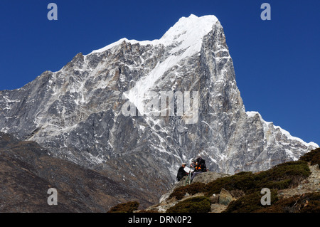 Due escursionisti si prendono una pausa sul campo base Everest trek, con Taboche dietro Foto Stock