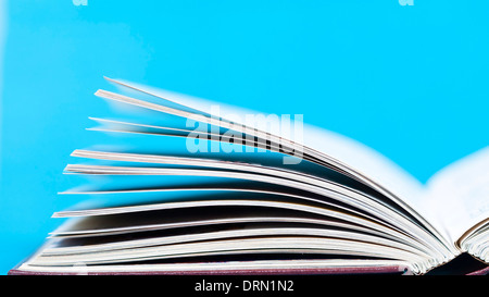 Libro aperto davanti a sfondo blu Foto Stock