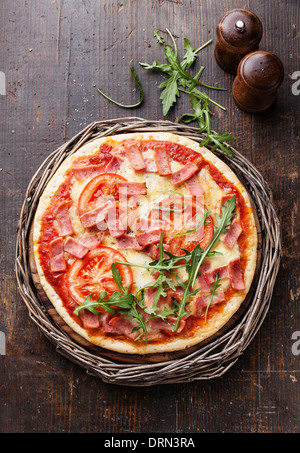 La pizza italiana con prosciutto e foglie di rucola sul tavolo di legno Foto Stock