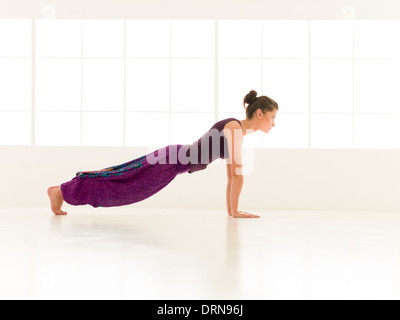 Piena vista laterale della giovane donna dimostrando equilibratura di Yoga asana vestiti colorati, illuminati backgrond finestra Foto Stock