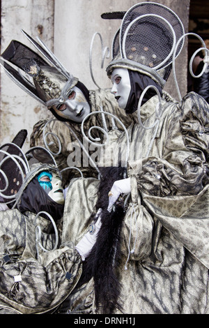 Tre in costume mascherato e i partecipanti del Carnevale di Venezia rappresenta per la folla. Foto Stock