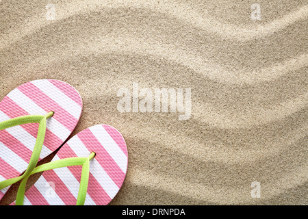 Spiaggia di sabbia con uno sfondo con flip flop. Concetto di estate. Vista superiore Foto Stock