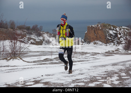 Un runner fa il suo modo attraverso la neve all'inizio della corsa. Foto Stock