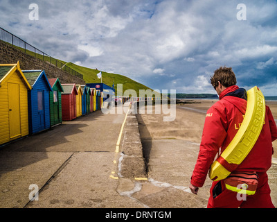 Vista posteriore di una guardia di vita e capanne da spiaggia di RNLI maschio caucasici, Whitby, North Yorkshire. Foto Stock