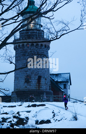 Un runner si fa strada su per la collina fino al mare e fino verso la casa di luce sul martello Knude. Foto Stock