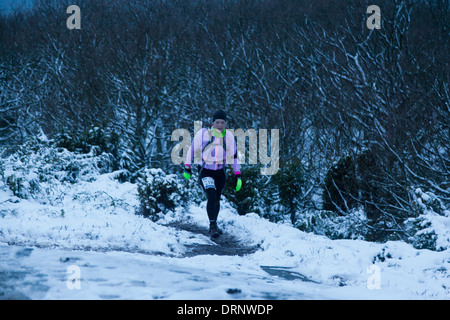 Un runner si fa strada su per la collina dal mare, attraverso boschi e in alto verso la casa di luce sul martello Knude. Foto Stock