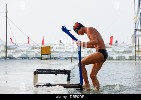 Nuotatore di ghiaccio fuoriesce dell'acqua fredda del fiume Songhua, Harbin, Cina. Un buco nel ghiaccio viene mantenuta aperta per il nuoto. Foto Stock