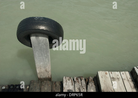 Vecchia auto pneumatici usati come un parafango su un fatiscente pontile in legno vicino Lyttleton, South Island, in Nuova Zelanda. Foto Stock