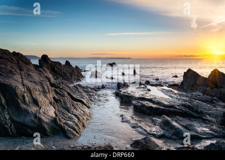 Sunrise ad una spiaggia di roccia a Looe in Cornovaglia Foto Stock