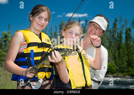Una Madre veglia le sue figlie tenendo un estate walleye catturati in un Ontario del nord fiume. Foto Stock