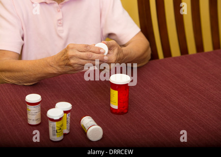 Femmina 74 enne senior citizen organizza il suo farmaco di prescrizione farmaci mentre a casa Foto Stock