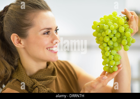 Felice giovane donna che guarda sul ramo delle uve Foto Stock