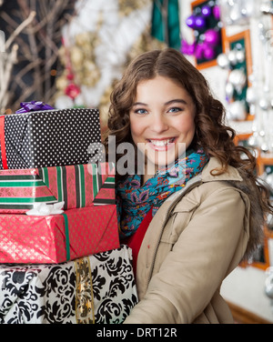 Donna che trasportano impilati i regali di Natale nel negozio Foto Stock