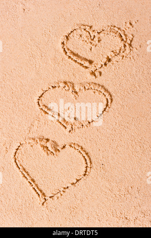 Tre cuori attirato sulla sabbia bagnata Foto Stock