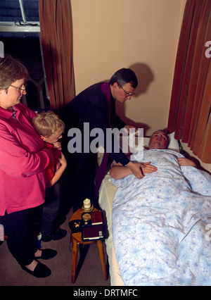 Sacrement del malato sacerdote unzione mani membri della famiglia presenti ultimi riti Foto Stock