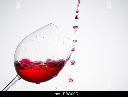 Versando il vino in un vetro di composizione diagonale e sfondo bianco Foto Stock