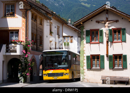 Autobus da turismo passa Christian crocifisso su una casa tradizionale in Mustair, Switzerlan Foto Stock