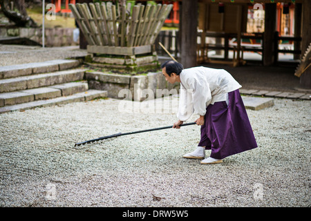 Lo Shintoismo giapponese sacerdote rastrelli un Giardino Zen. Foto Stock