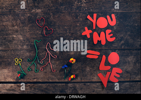 Amore creativo messaggio. Giovane holding hands realizzato da fermagli per carta e e thumbtacks su vintage sfondo di legno. Foto Stock