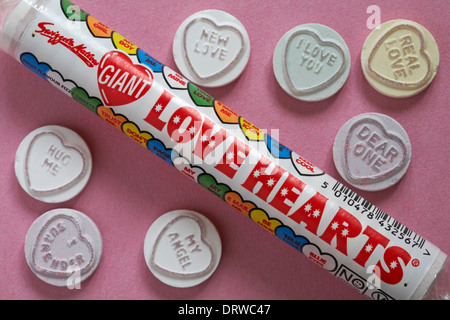 Pacchetto di Swizzels Matlow cuori di Amore Gigante con dolci individuali su sfondo rosa - ideale per San Valentino, giorno di San Valentino - dolci a cuore di Loveheart Foto Stock