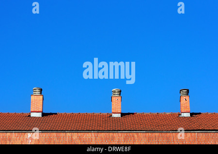 Camini sul tetto di casa contro un cielo blu Foto Stock